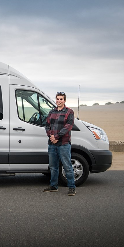 Owner of Oregon Coast Tours standing in front of his van next to the beach on the Oregon Coast