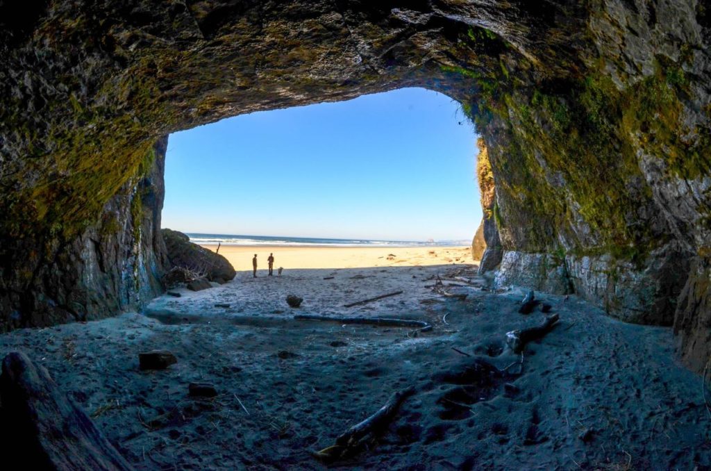 Large rocky arch on the beach in Pacific City, Oregon with a view of the ocean on a sunny day