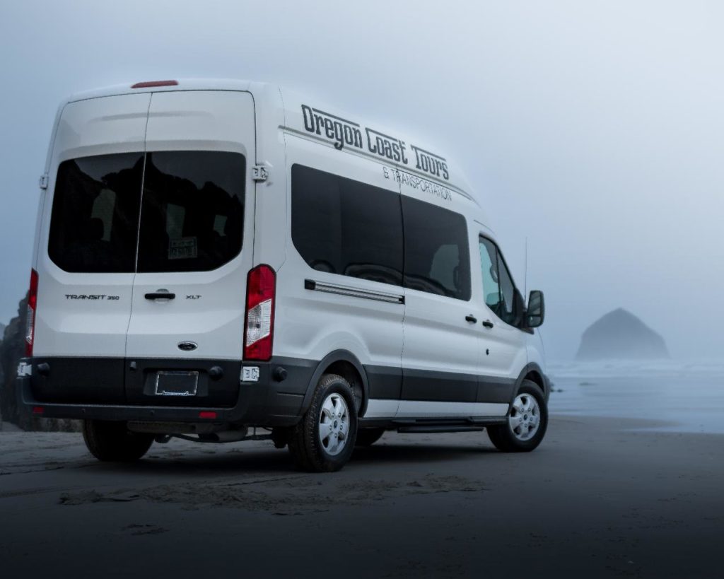 Oregon Coast Tours and Transportation van on Cannon Beach overlooking Haystack Rock on a foggy day